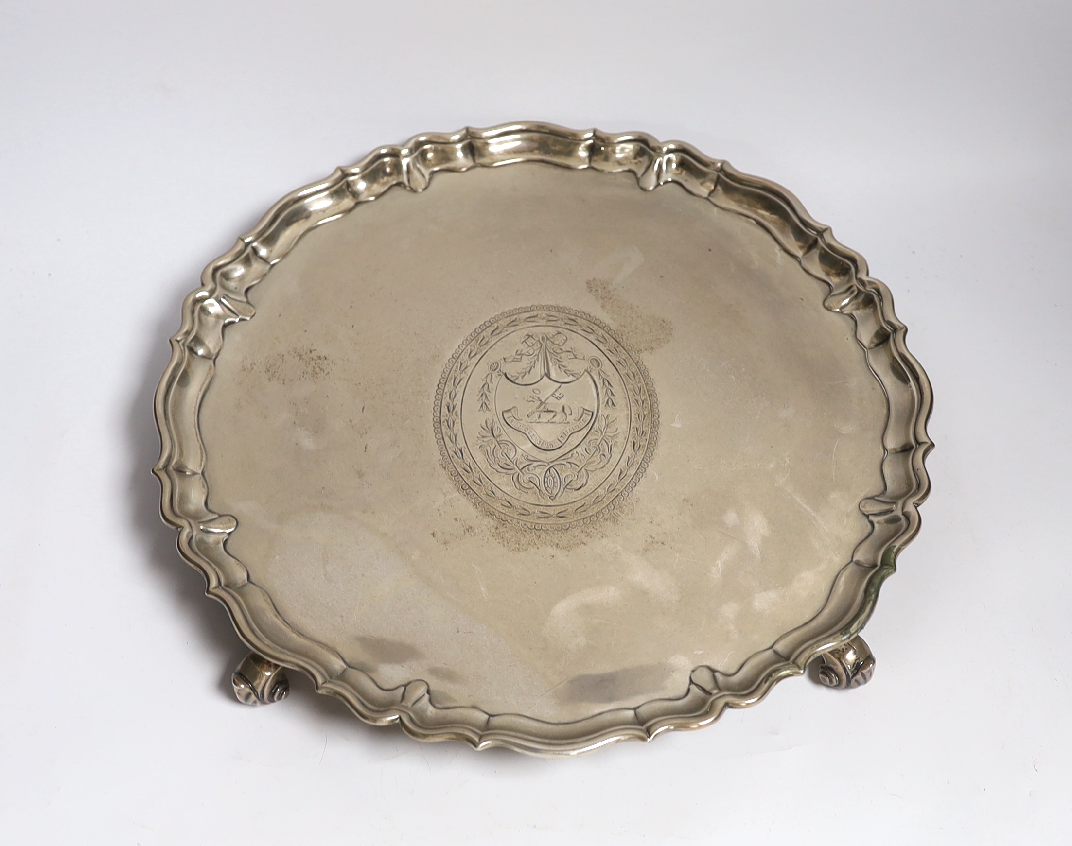 A large George II silver shaped circular salver, with pie crust border and engraved armorial, on four scroll feet, by John Tuite, London, 1735, diameter 36.6cm, 43.1oz.